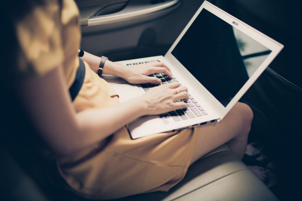 A woman sitting in a car using a laptop computer